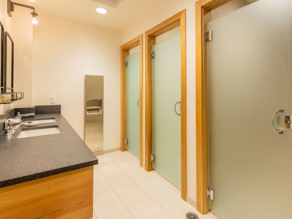 Modern bathroom: granite double sinks, tiled floor, wooden doors, and glass shower panels.