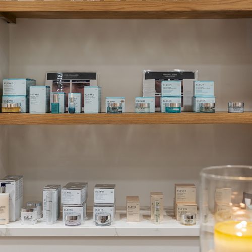 Shelves display multiple Elemis skincare bottles and boxes in a beauty shop.