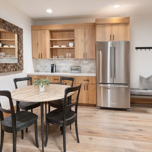 Modern kitchen with wooden cabinetry, a bench seating area, refrigerator, and a round table for dining.